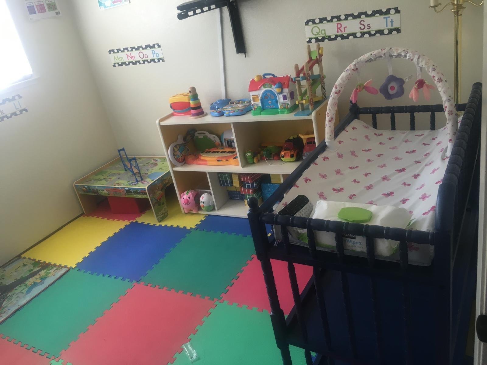 Baby room with a crib, colorful floor mats, and low shelves