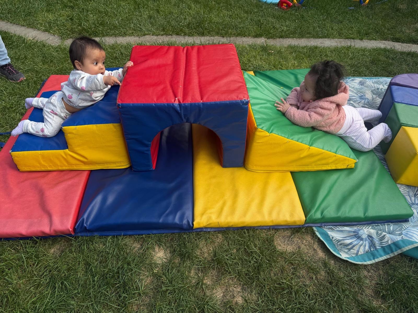 Young children exploring soft play shapes outdoors