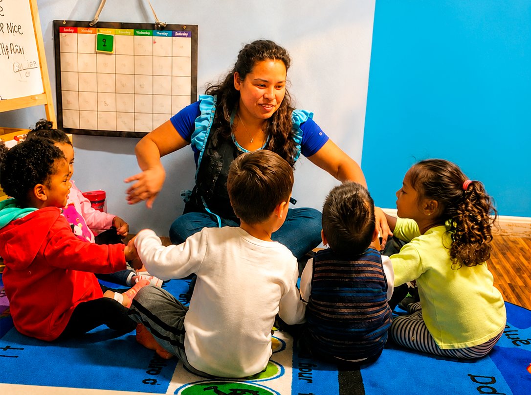 Sandra leading circle time with children on the learning rug