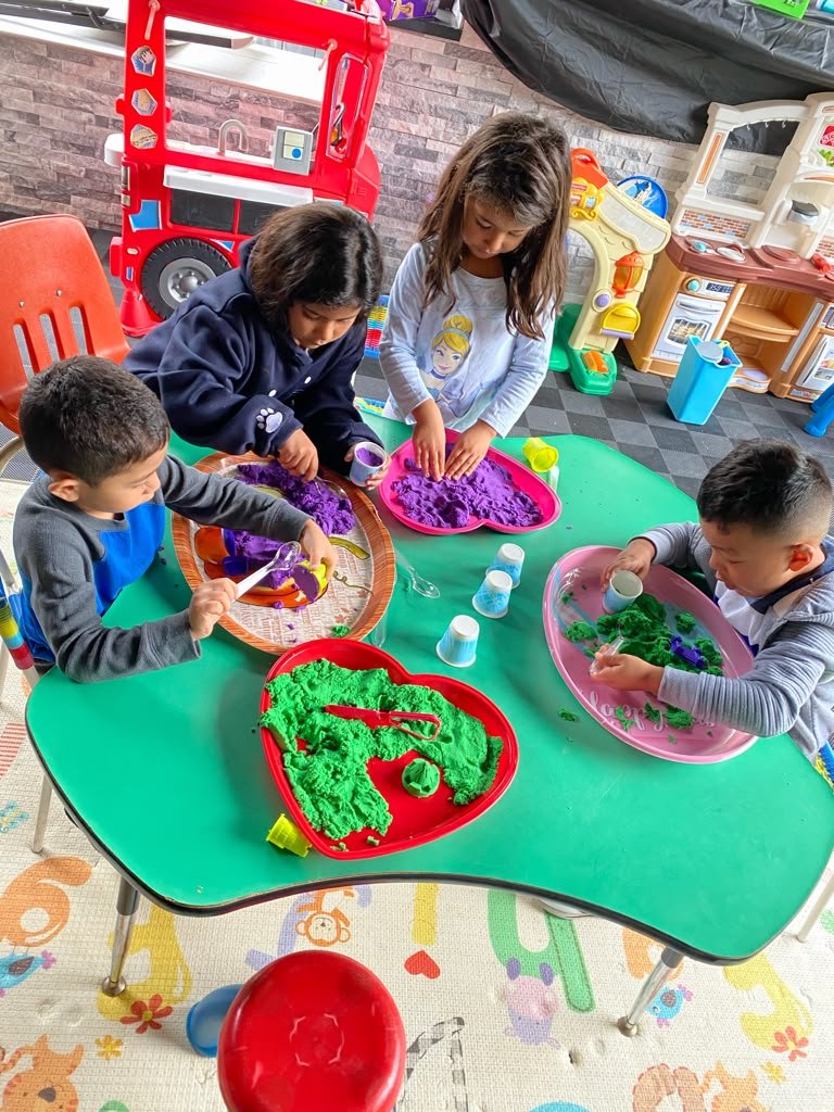 Children exploring colorful materials together at an activity table
