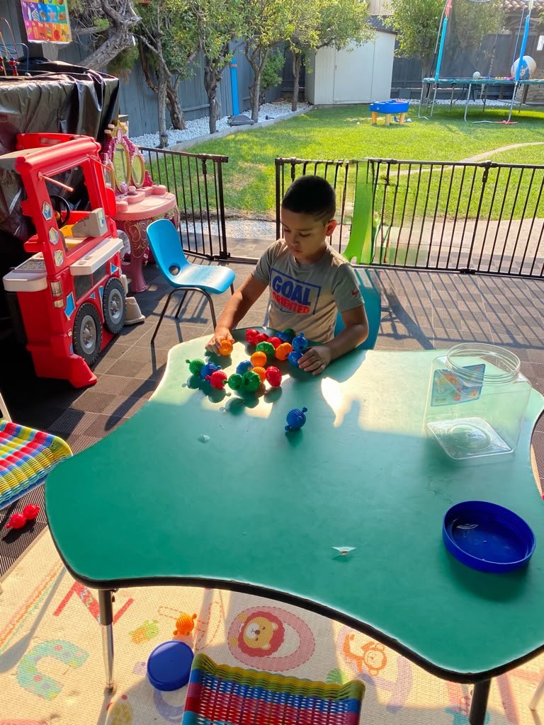 Child exploring colorful building toys at an outdoor table